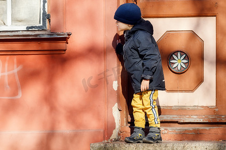 一个穿着秋装的可爱小男孩戴着帽子在老城散步