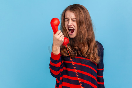 女人在用固定电话通话时尖叫，在呼叫中心与烦人的客户交谈。