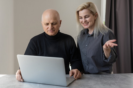 前视快乐的 70 年代灰发老人使用计算机软件与有爱心的成年女儿、退休老人和现代技术理念一起学习