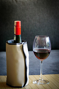 木质背景上带热冷却器和酒杯的红酒瓶