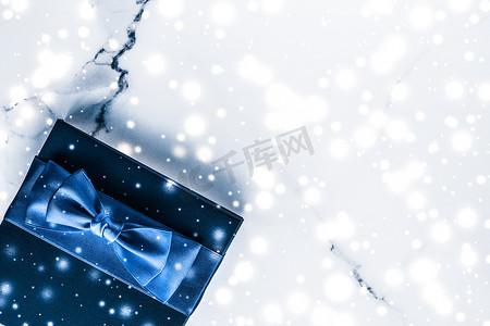 狗爪平铺摄影照片_冬季节日礼盒，配有蓝色丝绸蝴蝶结、大理石背景上的雪花，作为豪华美容品牌的圣诞和新年礼物，平铺设计