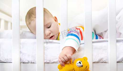 床上的男孩摄影照片_婴儿床上的婴儿去睡觉了。