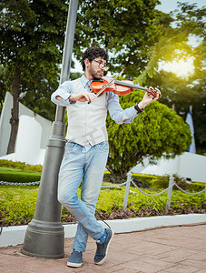 拉小提琴摄影照片_男子在街上拉小提琴。