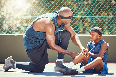 篮球膝盖受伤的孩子和爸爸一起在篮球场为运动训练比赛事故放置了紧急创可贴。