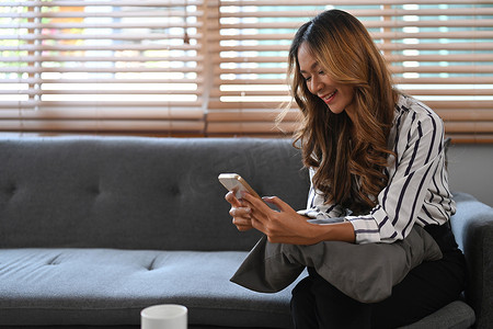 快乐的千禧一代女性使用手机、网上购物、在沙发上放松时订购送货。