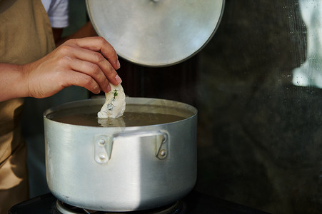 特写家庭主妇将生饺子浸入沸水中，酿造乌克兰瓦雷尼基。