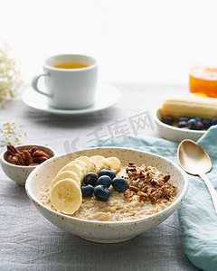 大杯香蕉牛奶摄影照片_早餐全麦片、一大碗香蕉粥、浆果、坚果。