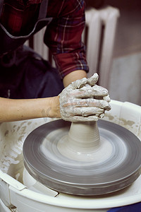 女人在轮子上制作陶瓷陶器，手特写。