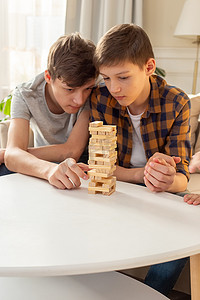 两个十几岁的男孩正在热情地玩由木制矩形块制成的棋盘游戏