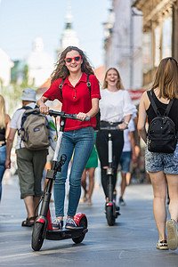 时尚时尚的少女在城市环境中骑着公共租赁电动滑板车。