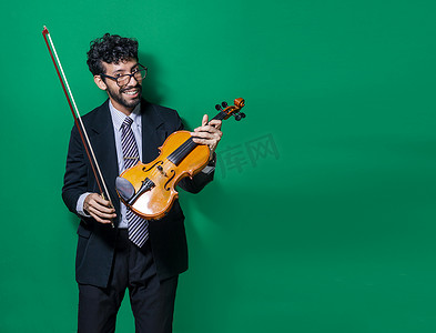 拿小提琴摄影照片_一个微笑的小提琴家的肖像被孤立，微笑的小提琴家看着相机，拿着他的小提琴，小提琴家的概念在孤立的背景下