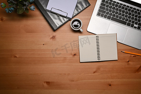 饮料区摄影照片_简单的工作区，木桌上配有笔记本电脑、笔记本和剪贴板。