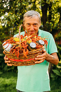 一位老祖父的肖像拿着一个大篮子，里面装着煮熟的红色大龙虾，微笑着享受生活
