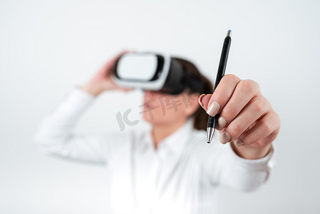 虚拟现实技术摄影照片_戴着 Vr 眼镜并用笔指着最近更新的女人。