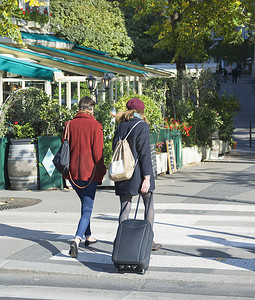 带着旅行手提箱或行李在巴黎街道上行走的女旅客