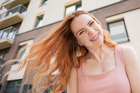 夏天户外时，牙齿上戴着牙套的漂亮红发年轻女子微笑着
