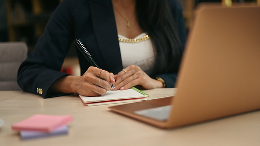 女性企业家在笔记本上写商业计划并在办公桌上使用笔记本电脑的剪影