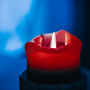蓝色和红色火焰摄影照片_蓝色背景的红色节日蜡烛、圣诞节、除夕和情人节的豪华品牌设计和装饰