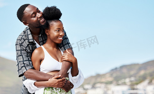 海滩上的年轻、爱情和黑人情侣在蓝天海滨风景中拥抱在一起。