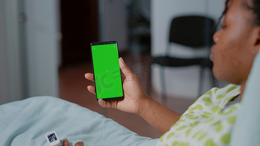 患者手持绿屏智能手机的特写