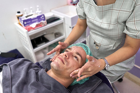 在进行面部美容治疗之前用手按摩患者的脸部