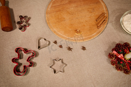 餐桌插图摄影照片_厨房亚麻桌布上的木板、擀面杖、饼干切刀和八角茴香调味料
