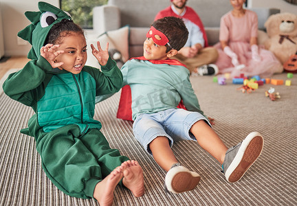 家庭、万圣节和孩子们穿着戏服在客厅的地板上玩耍，玩得开心，发挥创造力。