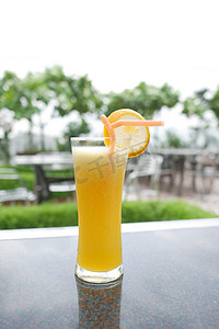 装橙汁的杯子摄影照片_户外桌上的一杯橙汁
