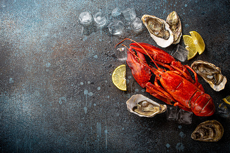 蓝龙虾摄影照片_蓝石质朴背景上的龙虾和牡蛎，配柠檬和冰块