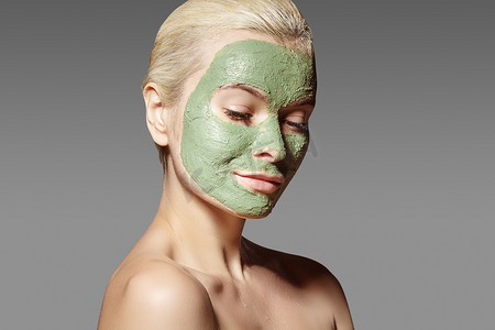 美丽的女人应用绿色面膜。