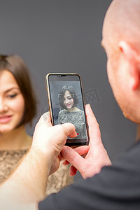 美发师在深色背景下为一位女士完成短发型拍照。