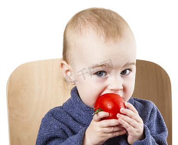 小孩子在高脚椅上吃西红柿