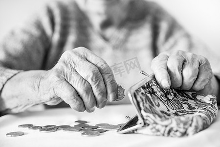 贫困老人摄影照片_详细的特写照片显示，无法辨认的老年妇女在支付账单后，双手数着钱包里养老金中剩余的硬币。