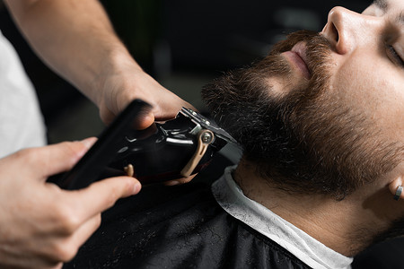 英俊的留胡子男子在理发店剪头发和胡须。