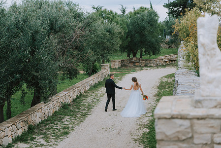 幸福天降摄影照片_幸福的时尚微笑夫妇在婚礼当天漫步在意大利托斯卡纳。