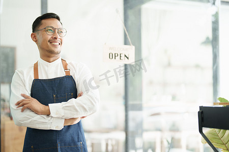 一位美丽的亚洲男子经营一家小企业，脸上露出笑脸，一位咖啡店老板在新的早晨开店欢迎顾客，中小企业概念