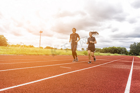 两名跑步者在赛道上慢跑、体育和社交活动概念