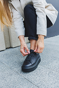 黑色系摄影照片_穿着黑色牛仔裤和黑色系带鞋的女性腿。
