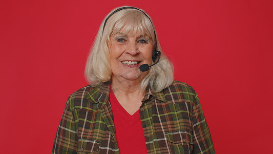 戴耳机的高级女性自由职业者呼叫中心或支持服务运营商热线电话交谈