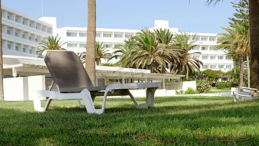 舒适的躺椅是您在拥有绿草和棕榈树的酒店休息区理想的休息和日光浴的场所。