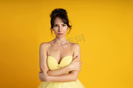 一位身穿黄色连衣裙的美丽中年妇女的肖像，她的头发在黄色背景下拉起