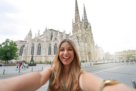 高兴极了摄影照片_心情很好的女人在法国波尔多大教堂前自拍