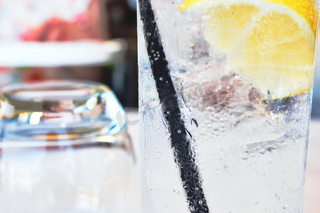 长玻璃杯中的冷软饮料，加冰、柠檬和黑吸管