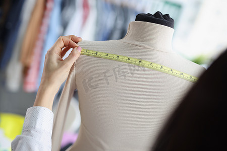 女裁缝测量人体模型背部以进行进一步缝纫