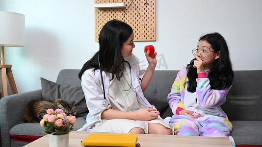和你一起玩摄影照片_两个亚洲女孩在家里扮演医生和病人。