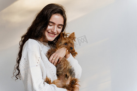 年轻有魅力的女人与狗约克夏犬微笑。