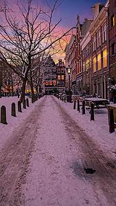 下雪的阿姆斯特丹在冬天在荷兰日落
