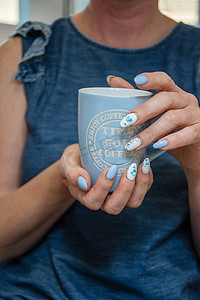 一位年轻女子拿着一杯蓝色咖啡，美丽的夏日美甲