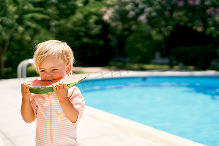 小女孩站在泳池边吃西瓜