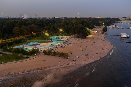 克雷斯托夫斯基岛黄昏时分照明的户外运动场、公共海滩、游艇俱乐部码头，人们在夏日的夜晚享受乐趣，天空的倒影